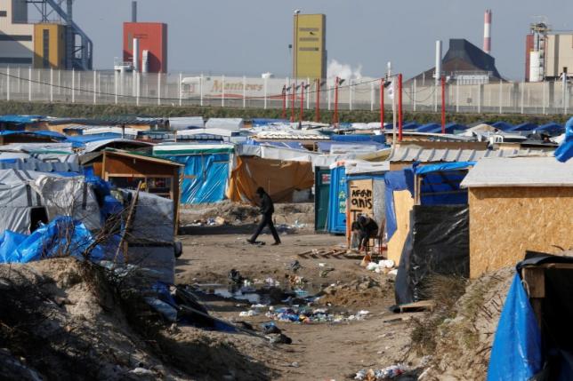 A migrant walks past makeshift shelters in the northern area on the final day of the dismantlement of the southern part of the camp called the ‘Jungle” in Calais